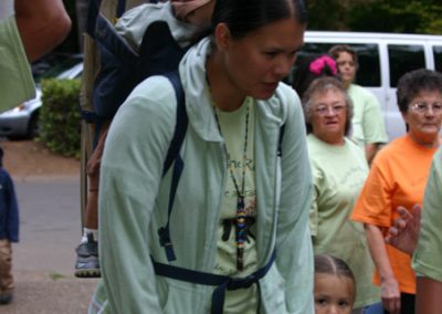 A woman carrying a baby on her back and holding the hand of a toddler at the Run to the Rogue event