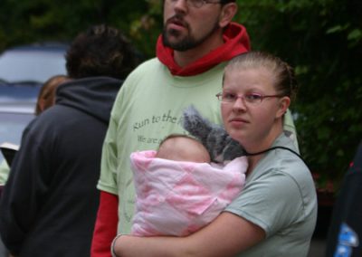 A man standing behind a woman who's holding a baby in a blanket at the Run to the Rogue event