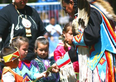 Elder giving money blessings to young pow-wow dancers.