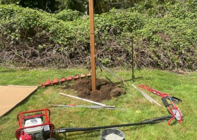 A wooden post placed into freshly dug dirt that will help create a garden fence.