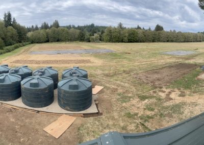 Panoramic shot of the property. There are 8 water collection tanks off to the left hand side.